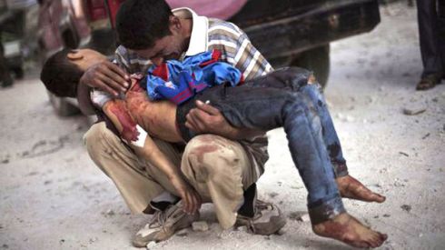 Un padre llora mientras sostiene a su hijo en brazos cerca del hospital de Alepo (Siria).